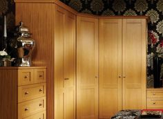 a bedroom with wooden cabinets and floral wallpaper on the walls, along with a bed