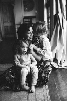 a woman sitting on the floor with two small children