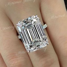 a woman's engagement ring with an emerald cut diamond in the center and side stones on