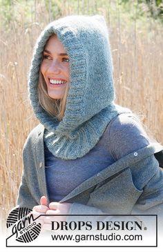 a woman wearing a gray hoodie and scarf in front of some tall brown grass