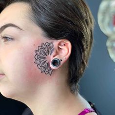 a woman with ear piercings on her nose and behind her ear is a flower