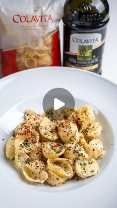 a white plate topped with pasta next to a bottle of wine and a bag of chips