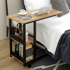 a laptop computer sitting on top of a wooden table next to a bed with white sheets