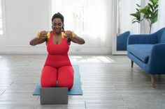 a woman sitting on the floor with two dumbs in front of her face and one arm behind her head