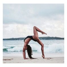 a woman doing a handstand on the beach