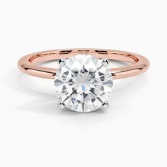 a rose gold engagement ring with diamonds on the band and a round cut diamond in the center