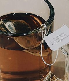 a glass mug filled with liquid sitting on top of a table next to a sign