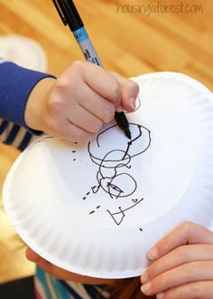 a child is drawing on a paper plate