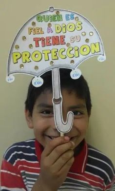 a young boy holding an umbrella over his face with spanish words written on the top