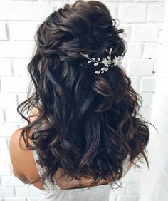 the back of a woman's head with long hair and flowers in her hair