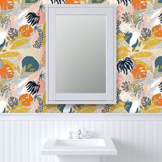 a bathroom sink sitting under a mirror next to a wallpapered wall covered in leaves