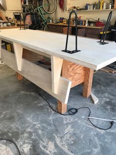 an unfinished workbench in a garage with tools on the table and wires attached to it