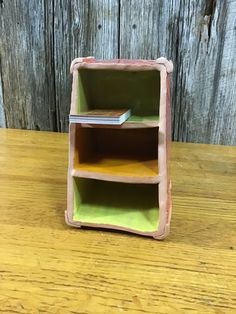 a book shelf sitting on top of a wooden table next to a wood plank wall