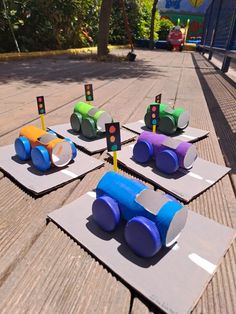 four different colored toy cars sitting on top of each other in the middle of a wooden floor