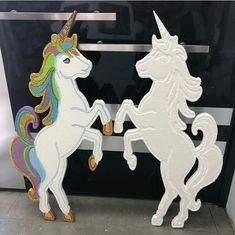 two unicorns standing next to each other in front of a black and white wall