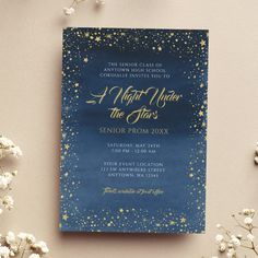 a blue and gold wedding card with stars on the front, sitting next to white flowers