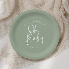 a green plate with the words oh baby written on it and a white lace background