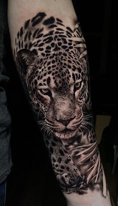 a black and white tattoo of a leopard on the arm