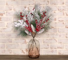 a vase filled with white and red flowers on top of a wooden table next to a brick wall