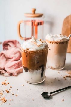 two drinks with whipped cream and chocolate on the top are sitting next to each other