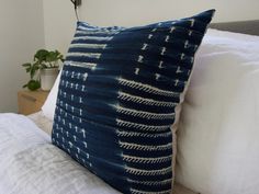 a blue and white pillow sitting on top of a bed