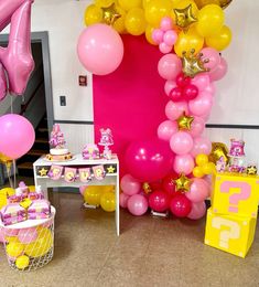 a room filled with lots of pink and yellow balloons