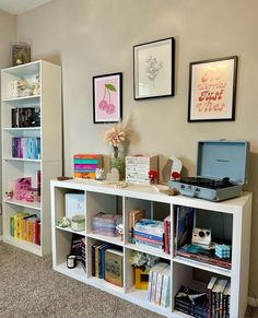 there is a book shelf with many books on it and pictures above the shelving