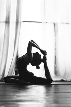 a woman is doing yoga in front of a window