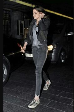 a woman in black and white checkered shoes is walking down the street at night