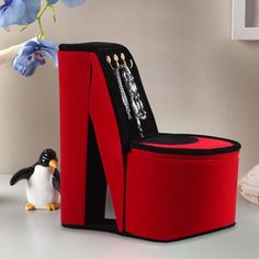 a penguin figurine next to a red chair with black and white decorations on it