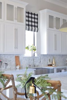 a kitchen with white cabinets and black checkered valance on the window sill