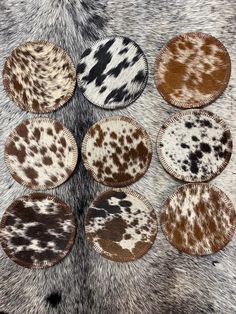 six brown and white animal print coasters sitting on top of a fur covered surface