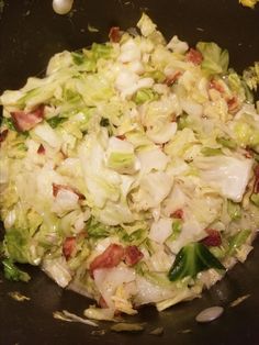 cabbage and bacon cooking in a wok on the stove top with some garlic flakes