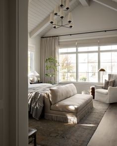 a large bed sitting in a bedroom next to a white couch and chair on top of a hard wood floor