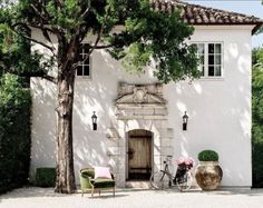 a white house with a bicycle parked in front of it and two chairs on the outside