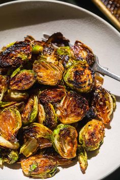 brussel sprouts in a white bowl with a fork on the side