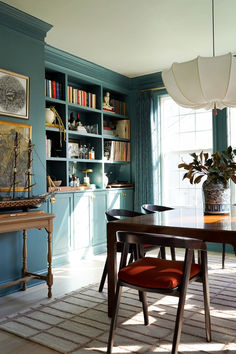 a dining room table and chairs with bookshelves in the background