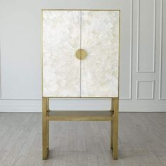 a white and gold cabinet sitting on top of a hard wood floor next to a wall