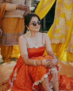 a woman sitting on the ground in an orange dress