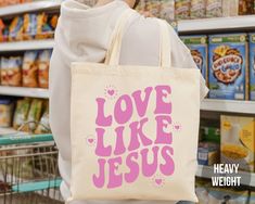 Spread a message of Faith with this cute Love Like Jesus Tote Bag! Our Heavyweight Christian Tote Bag is twice as thick as most Canvas Tote Bags! Reusable Grocery Bags are great for the environment too! ♥ Hello and Welcome to Meaningful Tees Shop! ♥ HEAVYWEIGHT TOTE: - 12 oz heavyweight fabric - More Durable - 15" wide x 16" high - 20" handles, 9" drop - Liberty Bags Brand - 100% Cotton Canvas - Spot Clean Only ♥ All of our items are made one at a time with care for each customer : ) ♥ Please al Affordable Preppy Bags For Everyday Use, Affordable Everyday Preppy Bags, Preppy Tote Bags, Bible Tote Bag, Diy Tote Bag Design, Handpainted Tote Bags, Christian Tote Bags, Sacs Tote Bags, Tods Bag