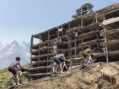 three bicyclists are riding on the side of a building that is under construction