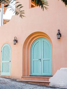 a pink building with two blue doors and green shutters