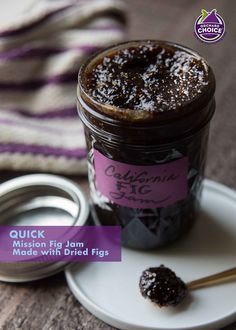 a jar of jam sitting on top of a white plate next to a purple label