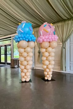 two tall balloons with donuts on them are in the middle of a large room