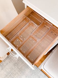 an open drawer on the side of a white table next to a rug and chair