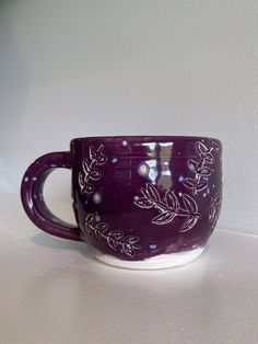 a purple coffee cup sitting on top of a white counter