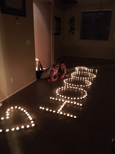 two children sitting on the floor in front of lighted letters