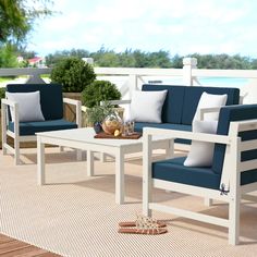 an outdoor patio furniture set with blue cushions and white frame, on a deck overlooking the water