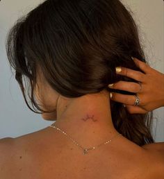 the back of a woman's neck with a small star tattoo on her left side