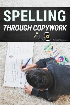 a young boy sitting on the floor writing in front of a sign that says spelling through copywork